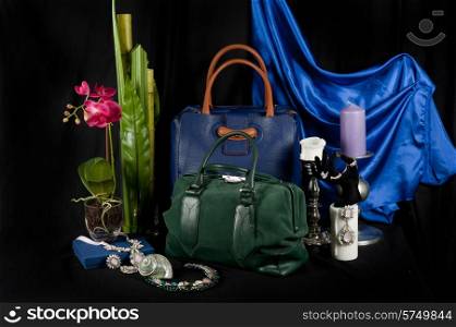 Fashionable handbag with jewelry and different items for composition on black background. . Fashionable handbag composition