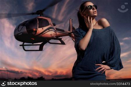 fashionable lady wearing sunglasses with helicopter in the background