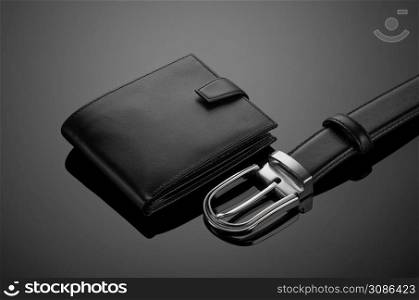Fashionable leather men&rsquo;s wallet and belt on a black background. men&rsquo;s wallet on a black background