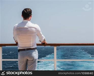 Fashionable man on the empty deck of a cruise liner against the backdrop of the sea waves. Side view, close-up. Concept of style, recreation and travel. Man on the empty deck of a cruise liner