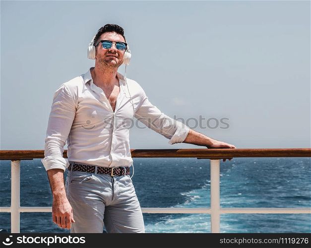 Fashionable man on the empty deck of a cruise liner against the backdrop of the sea waves. Side view, close-up. Concept of style, recreation and travel. Man on the empty deck of a cruise liner