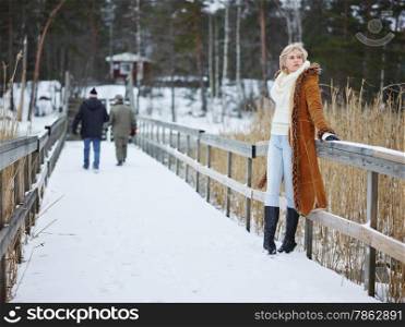 Fashionable mature adult woman wearing winter clothes and she standing next to the fence - rural scene