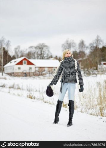 Fashionable mature adult woman wearing winter clothes, rural scene