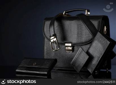Fashionable men&rsquo;s set of leather accessories on a dark background. Briefcase, wallet, belt. men&rsquo;s accessories on a black background