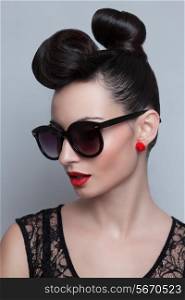 Fashionable model in trendy sunglasses. Plastic skin. Portraiture. Red lips. Updo, twisted high bun. top knot