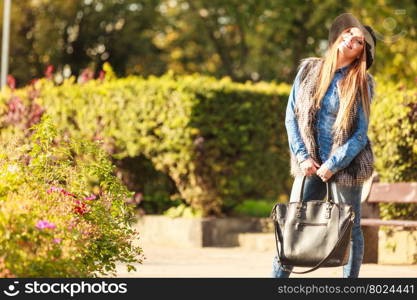 Fashionable model posing in park. Autumnal fashion of women. Attractive young stylish model posing outdoors. Fashionable girl wearing trendy clothes walking in park.