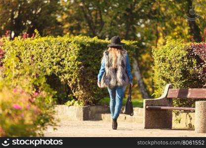 Fashionable model posing in park. Autumnal fashion of women. Attractive young stylish model posing outdoors. Fashionable girl wearing trendy clothes walking in park.