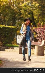 Fashionable model posing in park. Autumnal fashion of women. Attractive young stylish model posing outdoors. Fashionable girl wearing trendy clothes walking in park.
