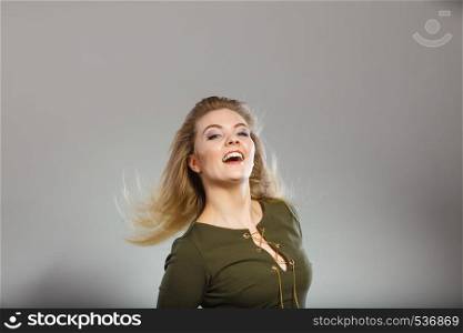 Fashionable outfit ideas, trendy clothes concept. Attractive blonde woman wearing tight dark green khaki top having windblown hair. Attractive blonde woman wearing tight green khaki top