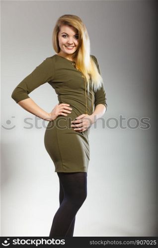 Fashionable outfit ideas, trendy clothes concept. Attractive blonde woman wearing tight dark green khaki dress. Attractive blonde woman wearing tight green khaki dress