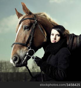 Fashionable portrait of a beautiful young woman and horse