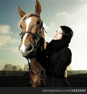 Fashionable portrait of a beautiful young woman and horse