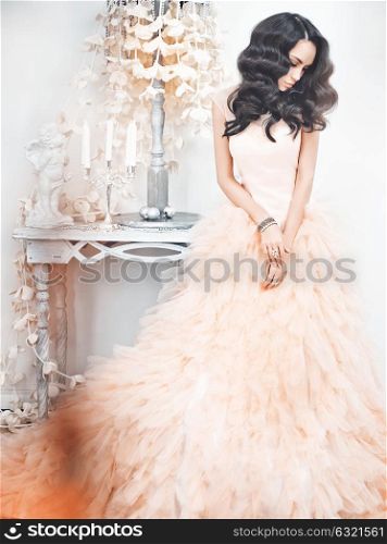 Fashionable portrait of beautiful lady in gorgeous couture dress in white interior. Holidays & Events. Evening dress. Princess dress. Christmas and New Year