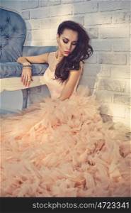 Fashionable portrait of beautiful lady in gorgeous couture dress on sofa