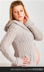 fashionable pregnant woman wearing woolen cardigan is looking sideways
