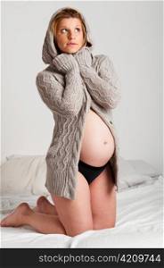 fashionable pregnant woman wearing woolen cardigan is looking upstairs