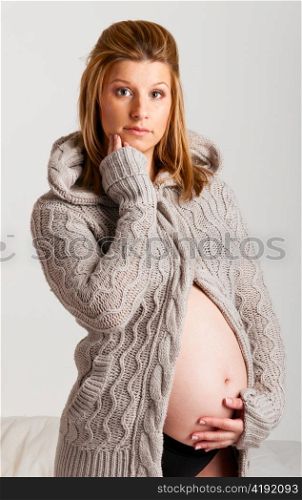 fashionable pregnant woman wearing woolen cardigan on gray background