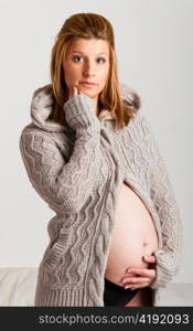 fashionable pregnant woman wearing woolen cardigan on gray background