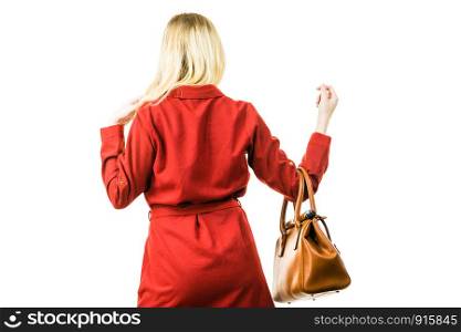 Fashionable pretty young woman wearing elegant casual red short dress and holding leather bag presenting stylish outfit.. Female wearing red dress holding bag