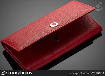 Fashionable red leather women&rsquo;s wallet on a dark background. women&rsquo;s wallet on a black background