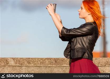 fashionable redhair tourist girl young woman taking photo picture with camera outdoor. Travel tourism and landmarks.