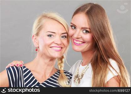 Fashionable style, clothes concept. Woman wearing white top standing next to older female with striped dress. Fashionable mother and daughter posing together