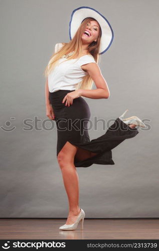 Fashionable style, clothes, good looking concept. Woman with brown hair wearing long black white dress and sun hat showing her leg.. Woman wearing long black white dress and sun hat