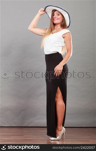 Fashionable style, clothes, good looking concept. Woman with brown hair wearing long black white dress and sun hat showing her leg.. Woman wearing long black white dress and sun hat