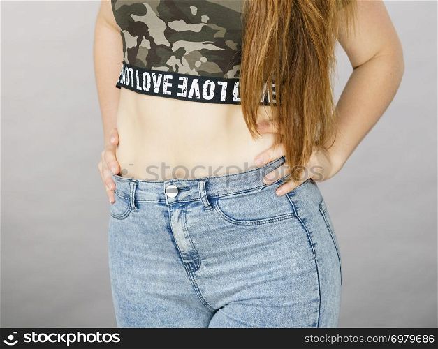 Fashionable unercognizable woman wearing jeans and crop top with green camo pattern.. Woman wearing jeans anc camo top