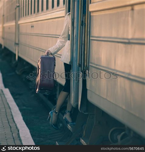 Fashionable woman entering into train car. Holding a suitcase