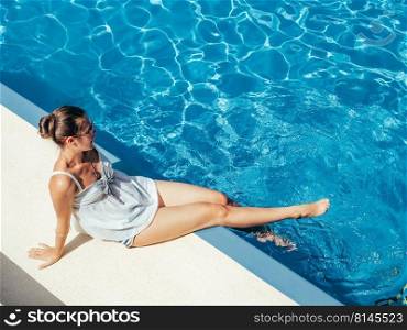 Fashionable woman sitting by the pool on the empty deck of a cruise liner. Closeup, outdoor. Vacation and travel concept. Fashionable woman sitting by the pool on the empty deck