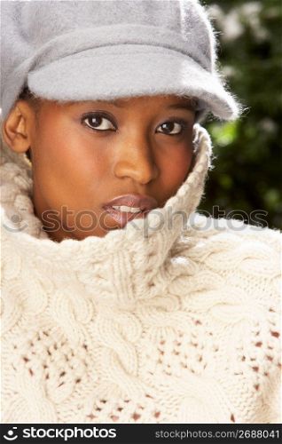 Fashionable Woman Wearing Knitwear And Cap In Studio In Front Of Christmas Tree