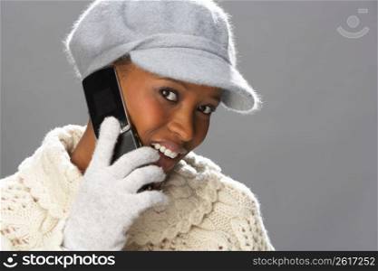 Fashionable Woman Wearing Knitwear And Cap In Studio Using Mobile Phone