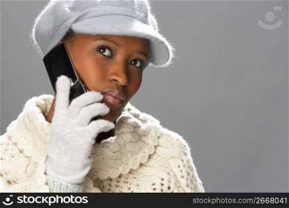 Fashionable Woman Wearing Knitwear And Cap In Studio Using Mobile Phone