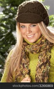 Fashionable Woman Wearing Knitwear And Scarf In Studio In Front Of Christmas Tree