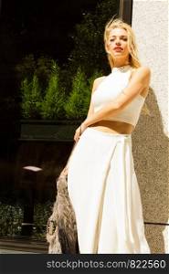 Fashionable woman wearing white outfit with wide trousers culottes and fur scarf, urban hipster fashion.. Woman wearing crop top and culottes