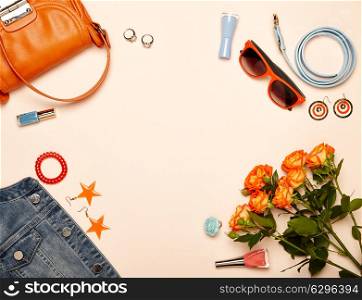 Fashionable Women&rsquo;s Cosmetics and Accessories. Falt Lay. Nail Polish and blush. Jewelry and Rings. A bouquet of flowers. Orange roses. Handbag and Denim Jacket