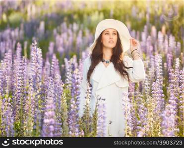 Fashionable young woman wearing a white hat and jacket, summery meadow