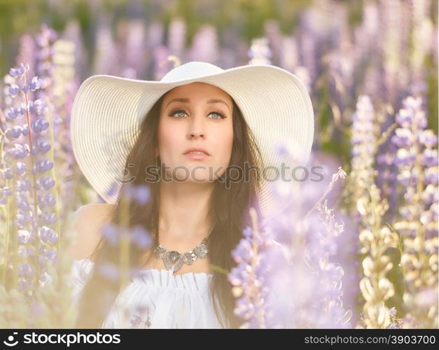 Fashionable young woman wearing a white hat and shirt, summery meadow