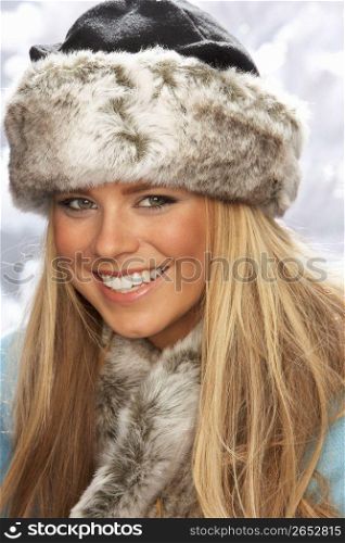 Fashionable Young Woman Wearing Fur Hat And Wrap In Studio With Artificial Christmas Tree
