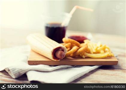 fast food and unhealthy eating concept - close up of deep-fried squid rings, french fries, drink and ketchup on wooden table