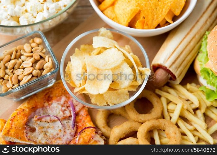 fast food and unhealthy eating concept - close up of different fast food snacks on wooden table. close up of fast food snacks and drink on table