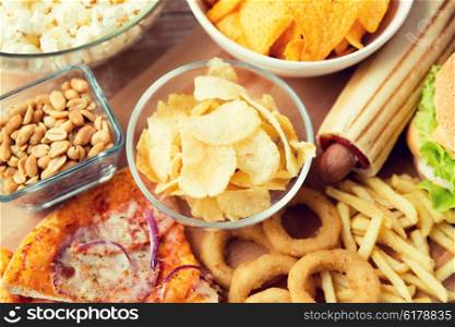 fast food and unhealthy eating concept - close up of different fast food snacks on wooden table. close up of fast food snacks and drink on table