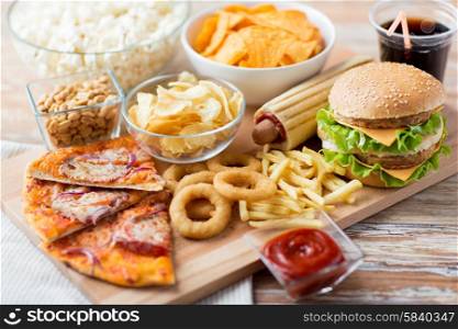 fast food and unhealthy eating concept - close up of fast food snacks and coca cola drink on wooden table. close up of fast food snacks and drink on table
