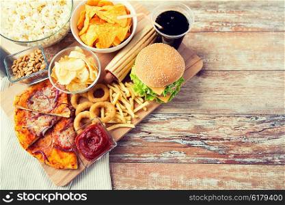 fast food and unhealthy eating concept - close up of fast food snacks and cola drink on wooden table. close up of fast food snacks and drink on table