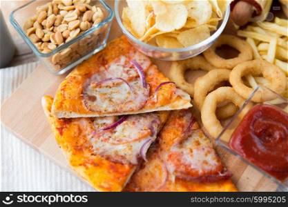 fast food and unhealthy eating concept - close up of pizza and other snacks on wooden table. close up of fast food snacks and drink on table
