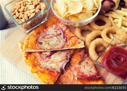 fast food and unhealthy eating concept - close up of pizza and other snacks on wooden table. close up of fast food snacks and drink on table