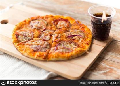 fast food and unhealthy eating concept - close up of sliced homemade pizza with cup of cola drink on wooden table. close up of homemade pizza with cola on table