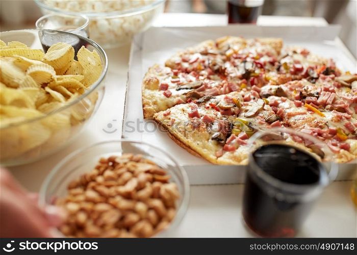 fast food and unhealthy eating concept - pizza, potato crisps and glass of cola drink on table. pizza and other fast food snacks on table