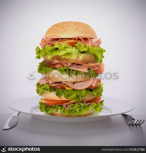 Fast food big sandwich with lettuce, tomato, smoked ham and cheese on plate